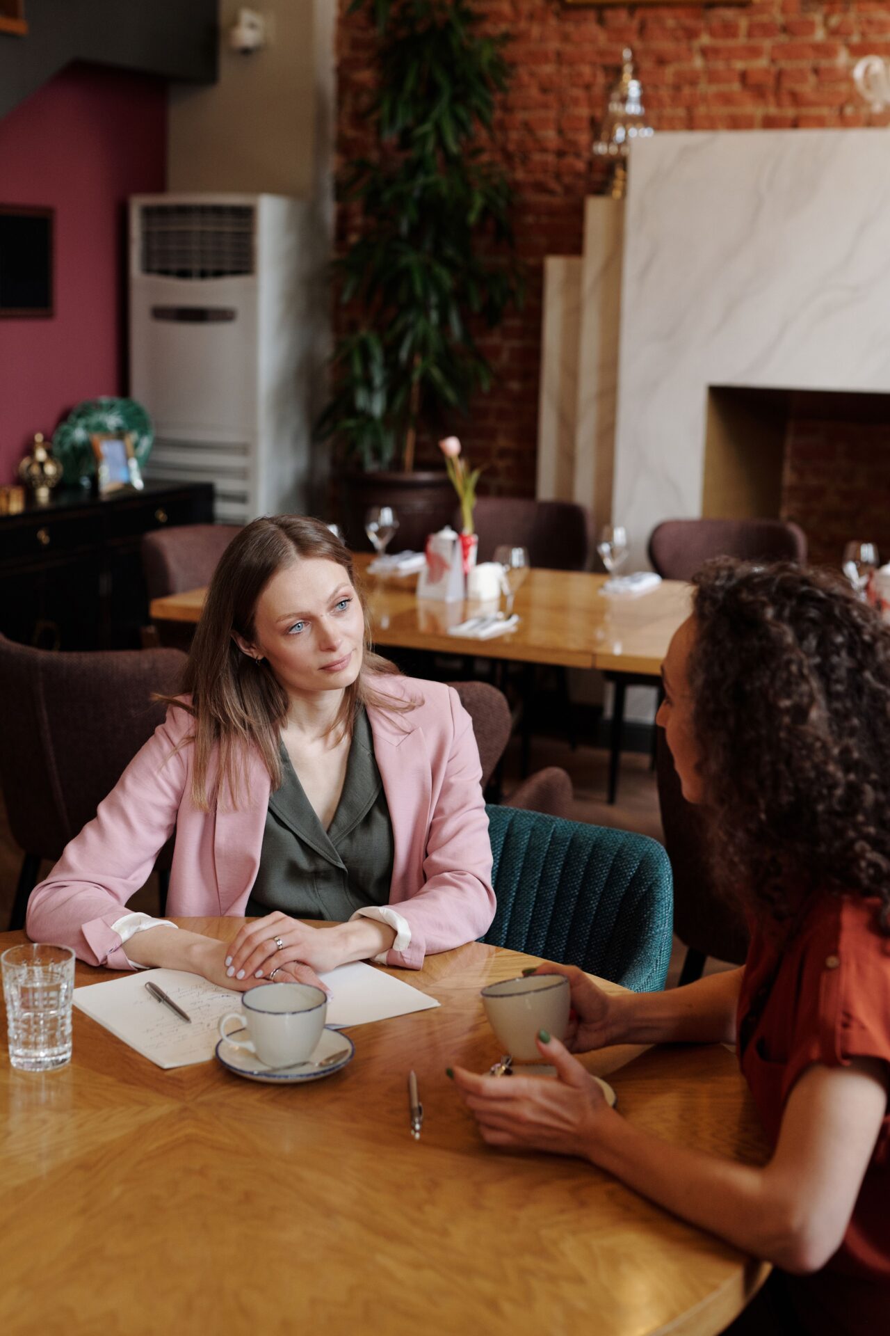 Twee vrouwen in gesprek aan tafel met notitieblok, BalansInzicht Preventiescan als startpunt voor een coachgesprek.